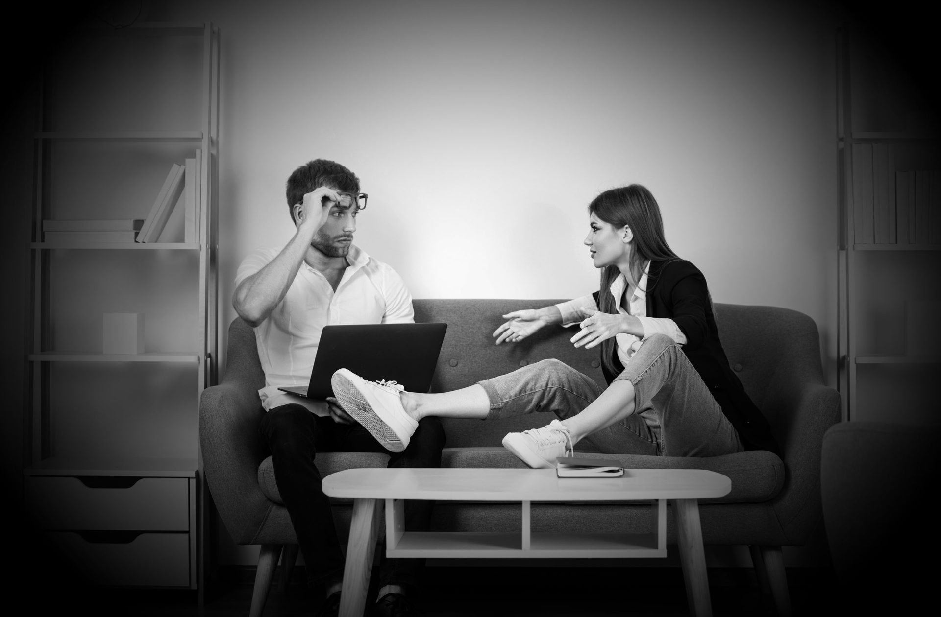 Moški in ženska v razpravi na kavču, črna in bela fotografija.