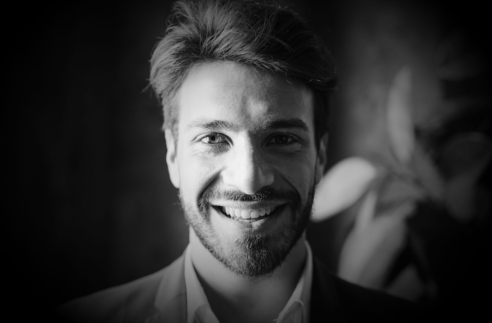 Svetel moški z nasmehom, portret v črno-beli barvi.